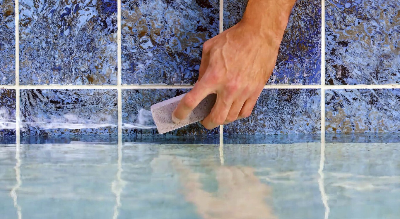 Hand scrubbing calcium deposits from pool tile in Castro Valley